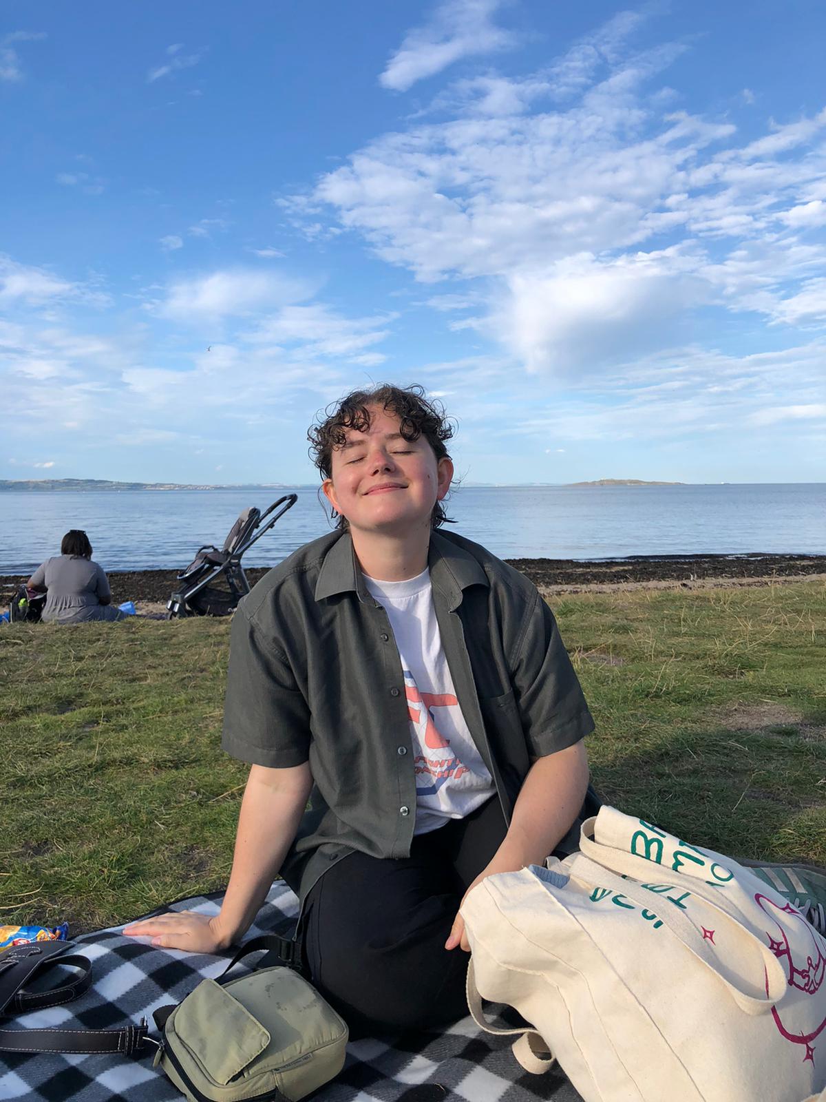 Person with a big smile and short hair at the beach